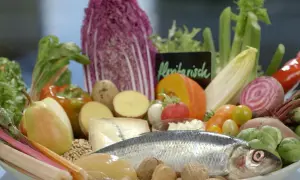 Frisches Gemüse, Fisch und Nüsse auf einem Teller. Eine gute Wahl für eine Ernährung bei Gicht, die auch Eier einschließen kann.