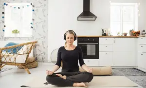 Frau meditiert mit Kopfhörern in einer Küche. Sie folgt einem 3-Minuten-Meditations-Text.