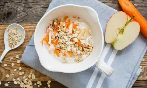 Schüssel mit Haferflocken, geriebenen Karotten und Apfelstücken. Selbst bei einer Haferflockenallergie kann man gesunde Alternativen finden.