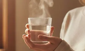 Hände halten ein Glas mit dampfendem, abgekochtem Wasser. Ein Schluck davon kann gesund sein.