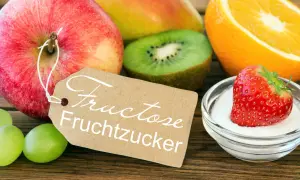 Obst und eine Erdbeere in Zucker, mit Schild "Fructose Fruchtzucker". Achtung bei Fructoseintoleranz!