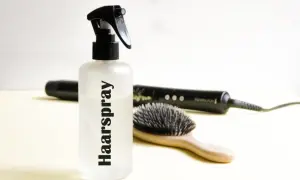 Flasche mit "Haarspray" Schriftzug, daneben Haarbürste und Glätteisen. Perfekt für haarspray selber machen.