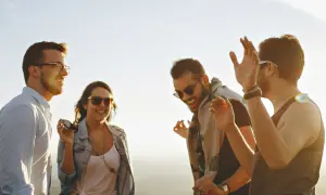 Vier Freunde lachen und tanzen ausgelassen in der Sonne. Sie zeigen, was sind echte freunde: Freude, Gemeinschaft und unbeschwerte Momente.