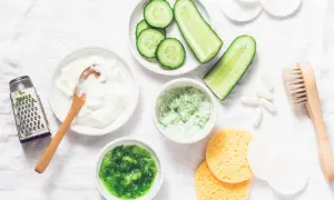 Zutaten für eine Gurkenmaske selber machen: Gurkenscheiben, Joghurt, geriebene Gurke, ein Hobel und weitere Utensilien.