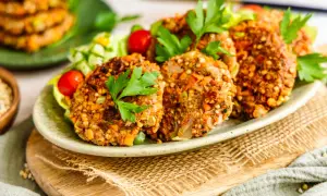 Herzhafte buchweizen bratlinge mit frischem Salat und Kirschtomaten, garniert mit Petersilie.