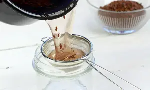 Flüssigkeit mit Leinsamen wird durch ein Sieb in ein Glas gegossen. Perfekt für leinsamen gesichtscreme selber machen.