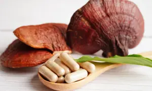 Reishi-Pilze und Kapseln auf einem Holzlöffel. Die Reishi-Wirkung auf die Psyche wird oft durch solche Präparate unterstützt.