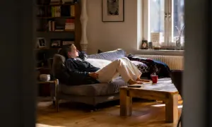 Frau entspannt sich auf dem Sofa, genießt das Sonnenlicht und praktiziert achtsame atem meditation.