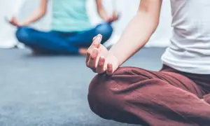 Zwei Personen in entspannter Haltung, die Meditation für die Psyche praktizieren. Hände in Mudras, Fokus auf innere Ruhe.