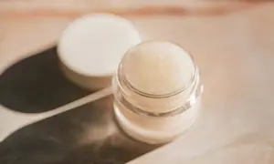 Ein kleiner Tiegel mit selbstgemachter Augencreme, daneben der Deckel. Perfekt für alle, die Augencreme selber machen wollen.