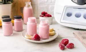 Erfrischender Erdbeer-Bananen-Smoothie, zubereitet im Thermomix. Kleine Gläser mit dem rosa Getränk, garniert mit frischen Früchten.