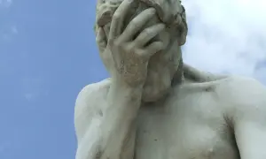 Marmorstatue mit verdecktem Gesicht im blauen Himmel. Ein Symbol für das Aushalten von Schmerzen, Tipps zur Bewältigung.