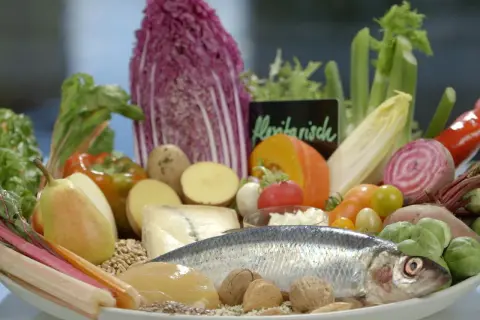 Frisches Gemüse, Fisch und Nüsse auf einem Teller. Eine gute Wahl für eine Ernährung bei Gicht, die auch Eier einschließen kann.