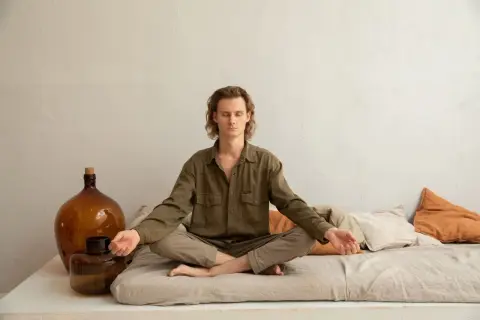 Mann in Lotusposition, Augen geschlossen, Arme entspannt. Ein Mann findet Ruhe durch Meditation gegen Depression.