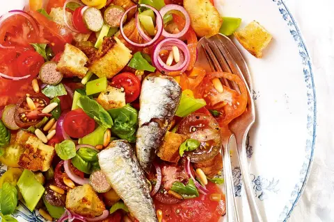 Bunter Salat mit Tomaten, Brot-Croutons, Zwiebeln und zwei ganzen Sardinen. Ein köstlicher Sardinensalat für den Sommer.