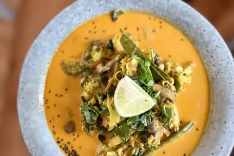 Ein cremiges Curry mit Brokkoli, Pilzen und Zuckerschoten, garniert mit Limette. Ein köstliches Beispiel für ayurvedische Rezepte.