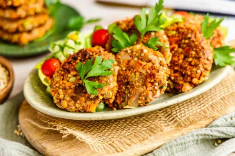 Herzhafte buchweizen bratlinge mit frischem Salat und Kirschtomaten, garniert mit Petersilie.