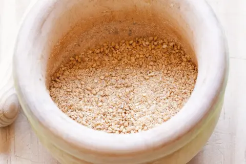 Mörser mit geröstetem Sesam und Salz für ein einfaches Gomasio Rezept.