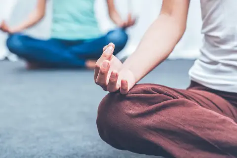 Zwei Personen in entspannter Haltung, die Meditation für die Psyche praktizieren. Hände in Mudras, Fokus auf innere Ruhe.