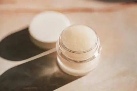 Ein kleiner Tiegel mit selbstgemachter Augencreme, daneben der Deckel. Perfekt für alle, die Augencreme selber machen wollen.