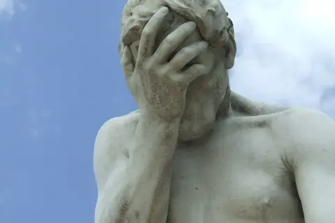 Marmorstatue mit verdecktem Gesicht im blauen Himmel. Ein Symbol für das Aushalten von Schmerzen, Tipps zur Bewältigung.