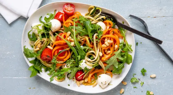 Bunter Zoodles Salat mit Karottenstreifen, Mozzarella-Kugeln, Kirschtomaten und Pinienkernen. Ein leichter Genuss!