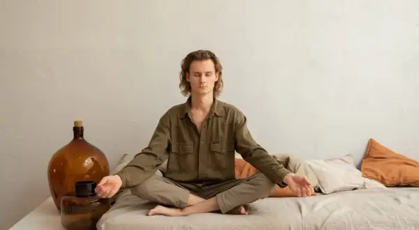 Mann in Lotusposition, Augen geschlossen, Arme entspannt. Ein Mann findet Ruhe durch Meditation gegen Depression.