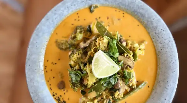 Ein cremiges Curry mit Brokkoli, Pilzen und Zuckerschoten, garniert mit Limette. Ein köstliches Beispiel für ayurvedische Rezepte.