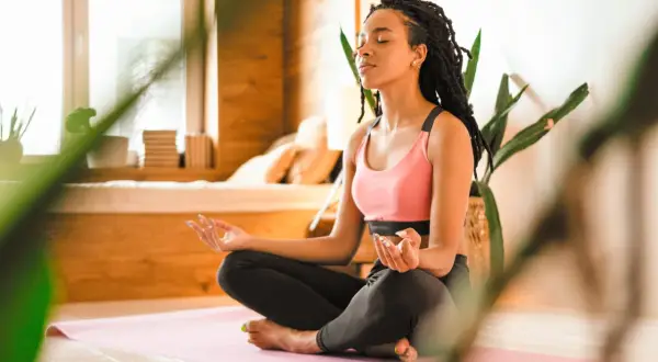Eine junge Frau meditiert in Lotusposition. Ihre Augen sind geschlossen, Hände im Gyan Mudra. Eine Szene, die an eine Zen-Meister Geschichte erinnert, voller Achtsamkeit und innerer Ruhe.