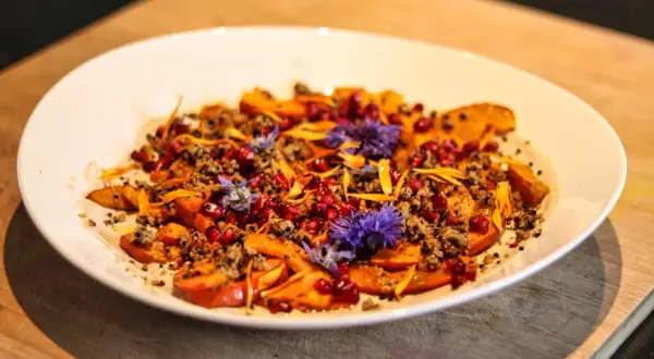Bunter Salat mit Kürbis, Granatapfelkernen und Blüten. Ein Gericht, das sich gut für Kapha Rezepte eignet.