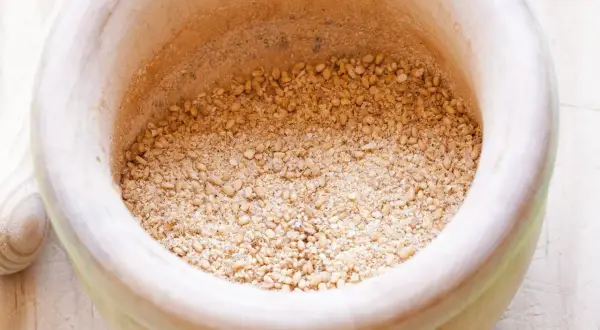 Mörser mit geröstetem Sesam und Salz für ein einfaches Gomasio Rezept.