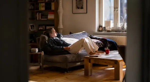 Frau entspannt sich auf dem Sofa, genießt das Sonnenlicht und praktiziert achtsame atem meditation.