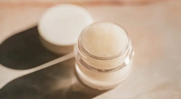 Ein kleiner Tiegel mit selbstgemachter Augencreme, daneben der Deckel. Perfekt für alle, die Augencreme selber machen wollen.