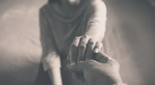 Zwei Hände halten sich fest. Die eine Hand ist zart, die andere wirkt kräftiger. Ein Symbol für Unterstützung, vielleicht gegen energievampire symptome.