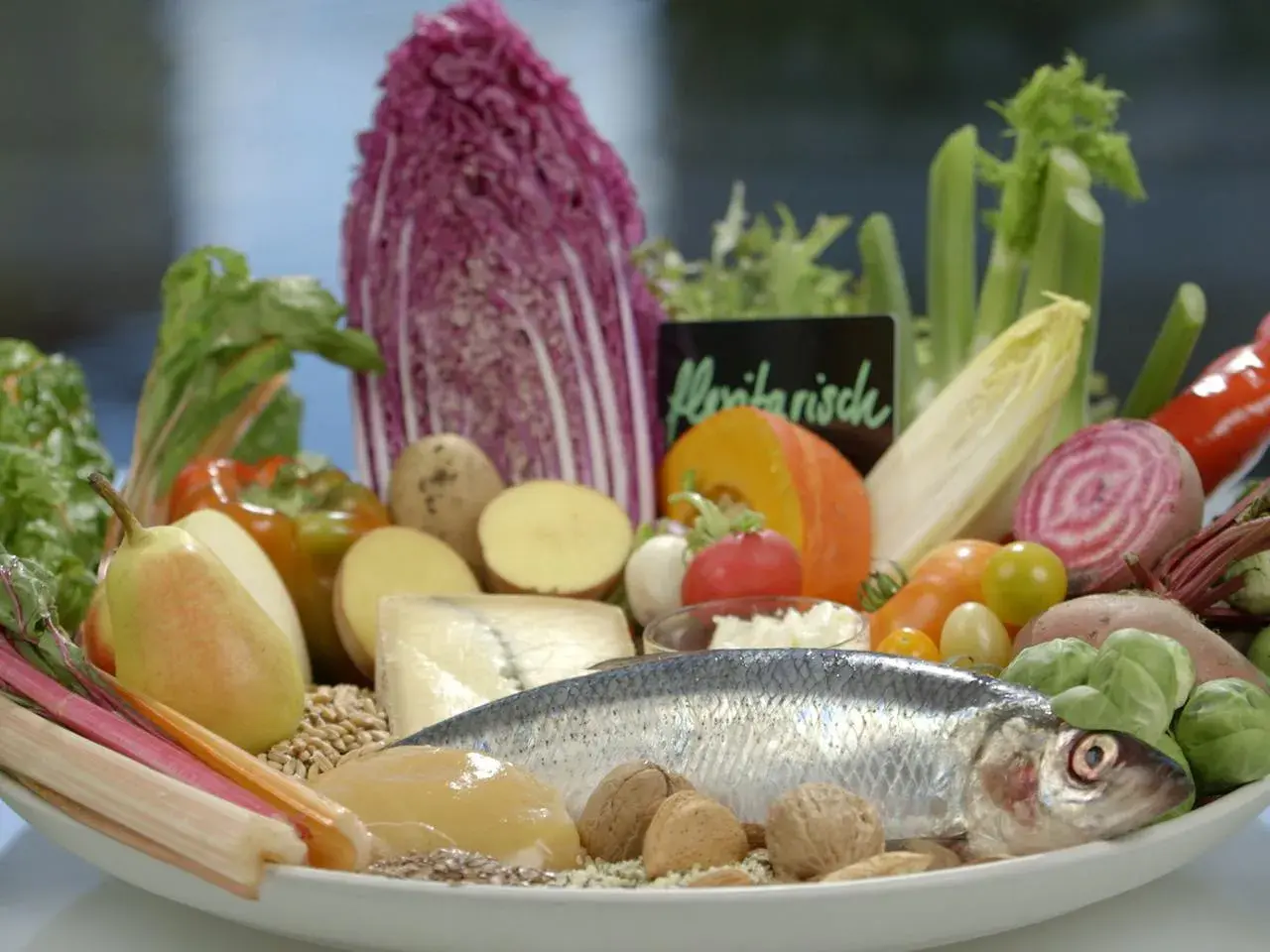 Frisches Gemüse, Fisch und Nüsse auf einem Teller. Eine gute Wahl für eine Ernährung bei Gicht, die auch Eier einschließen kann.