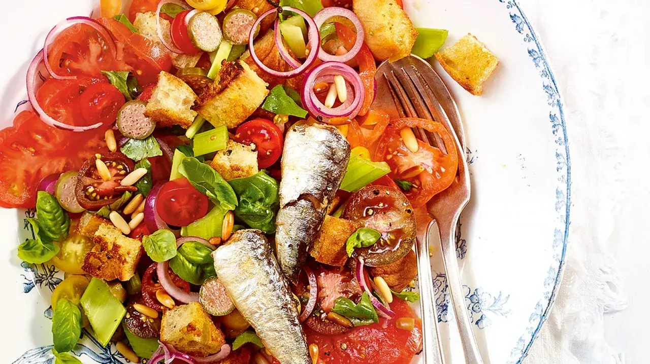 Bunter Salat mit Tomaten, Brot-Croutons, Zwiebeln und zwei ganzen Sardinen. Ein köstlicher Sardinensalat für den Sommer.