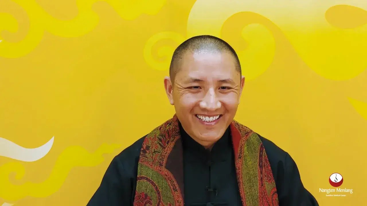 Ein Mann mit Glatze lächelt warm, trägt einen Schal und erklärt die Tummo Meditation.