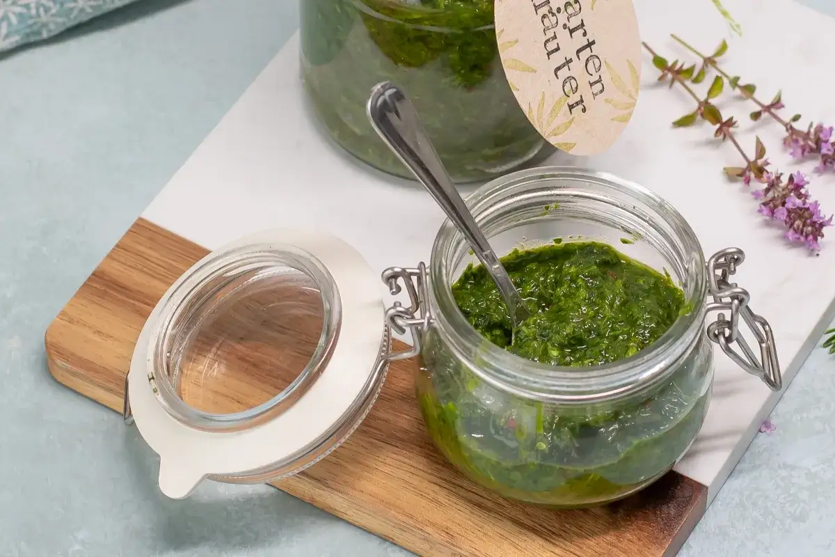 Frische Kr&auml;uter in Gl&auml;sern, perfekt zum Rosmarin Badezusatz selber machen. Ein L&ouml;ffel steckt in einem Glas mit gr&uuml;ner Masse.