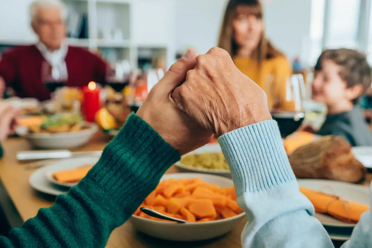 Familie h&auml;lt H&auml;nde vor dem gemeinsamen Gebet vor dem Essen.