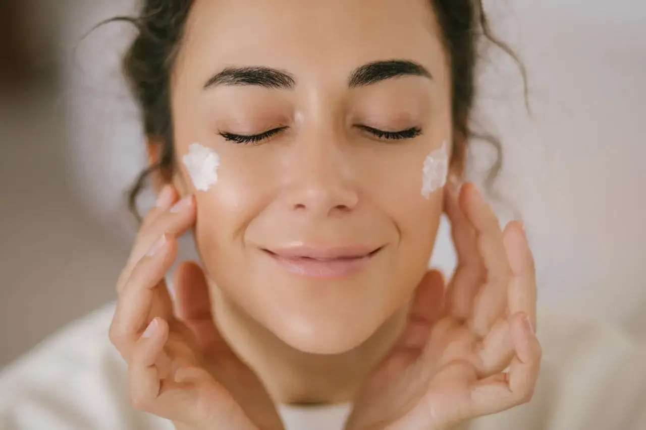 Frau mit geschlossenen Augen, die sich Creme mit Glycerin ins Gesicht auftr&auml;gt. Sanfte Ber&uuml;hrung f&uuml;r reine Haut.