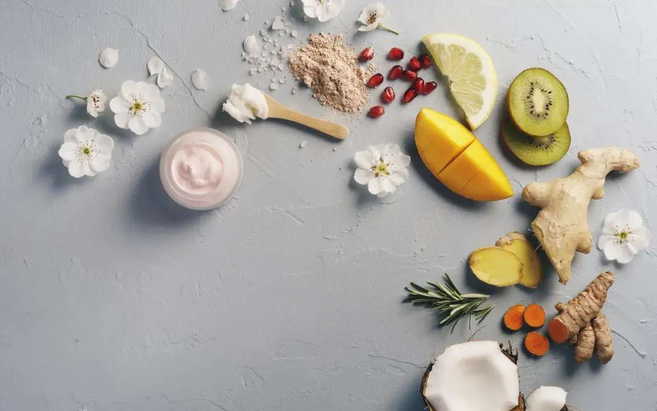 Nat&uuml;rliche Zutaten wie Mango, Kiwi, Ingwer und Kokosnuss, die f&uuml;r ihre positive triphala wirkung haut sind, umgeben eine rosa Creme.