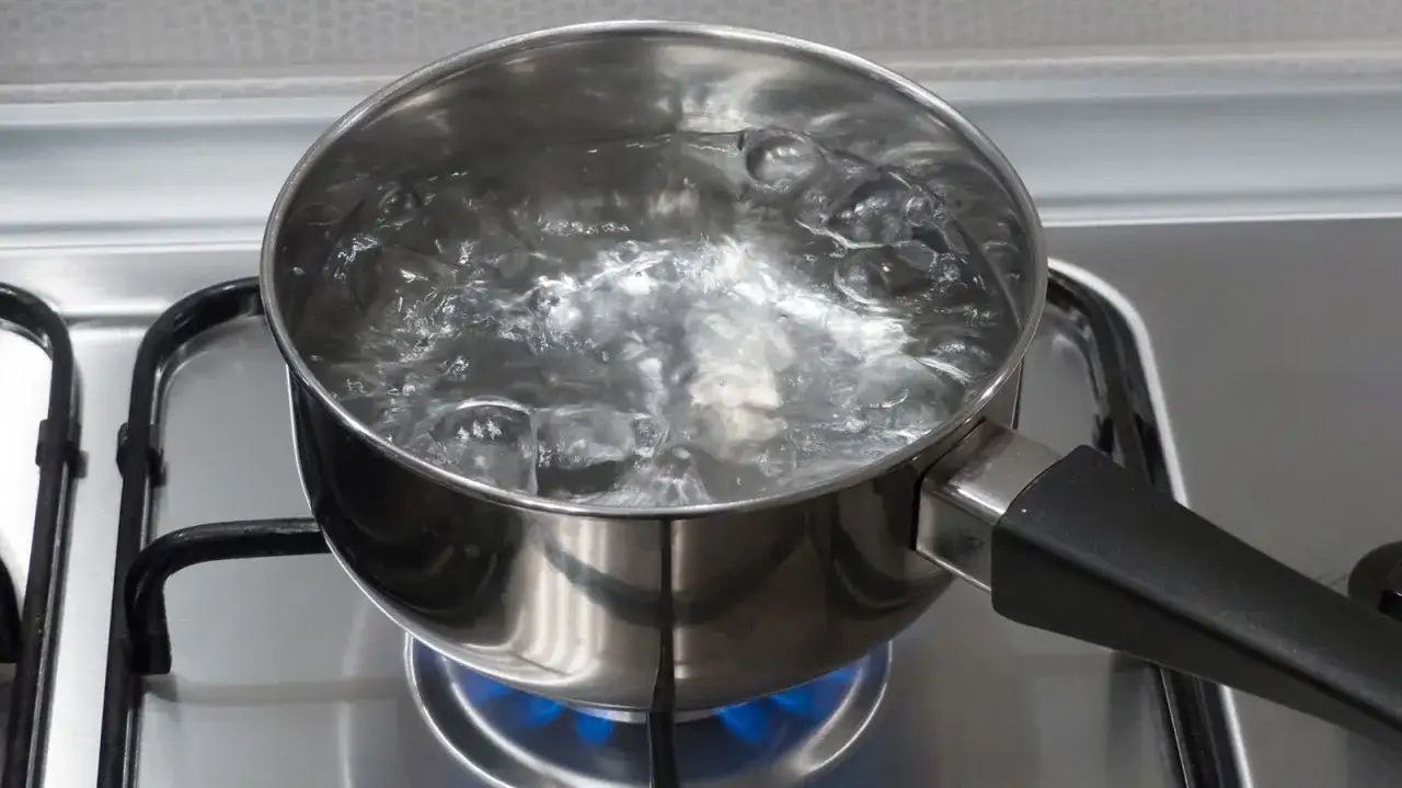 Ein Topf mit sprudelnd kochendem Wasser auf dem Herd. Abgekochtes Wasser ist gesund, da es Keime abt&ouml;tet und somit sicherer zu trinken ist.