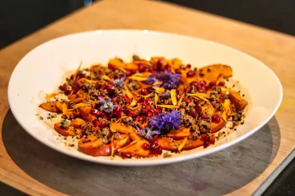 Bunter Salat mit Kürbis, Granatapfelkernen und Blüten. Ein Gericht, das sich gut für Kapha Rezepte eignet.