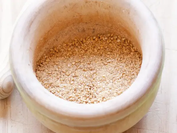 Mörser mit geröstetem Sesam und Salz für ein einfaches Gomasio Rezept.