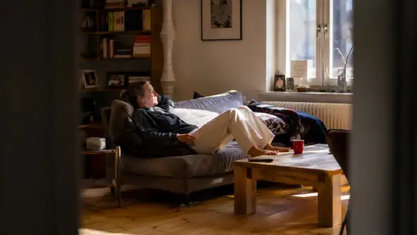 Frau entspannt sich auf dem Sofa, genießt das Sonnenlicht und praktiziert achtsame atem meditation.