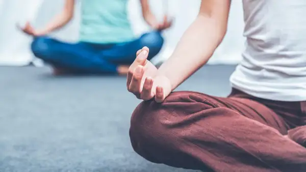 Zwei Personen in entspannter Haltung, die Meditation für die Psyche praktizieren. Hände in Mudras, Fokus auf innere Ruhe.
