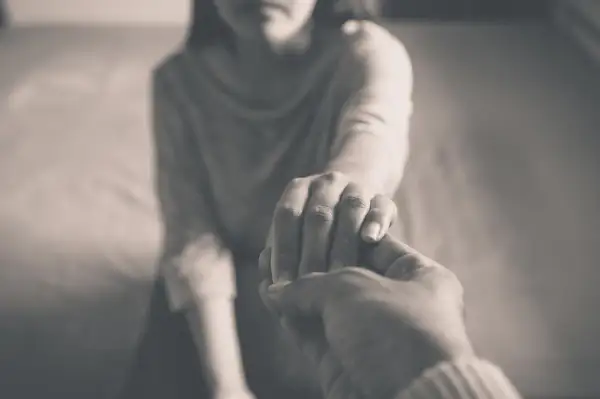 Zwei Hände halten sich fest. Die eine Hand ist zart, die andere wirkt kräftiger. Ein Symbol für Unterstützung, vielleicht gegen energievampire symptome.
