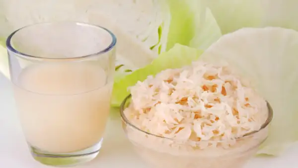 Ein Glas Sauerkrautsaft und eine Schüssel Sauerkraut, um die positive Sauerkrautsaft Wirkung Leber zu unterstützen.